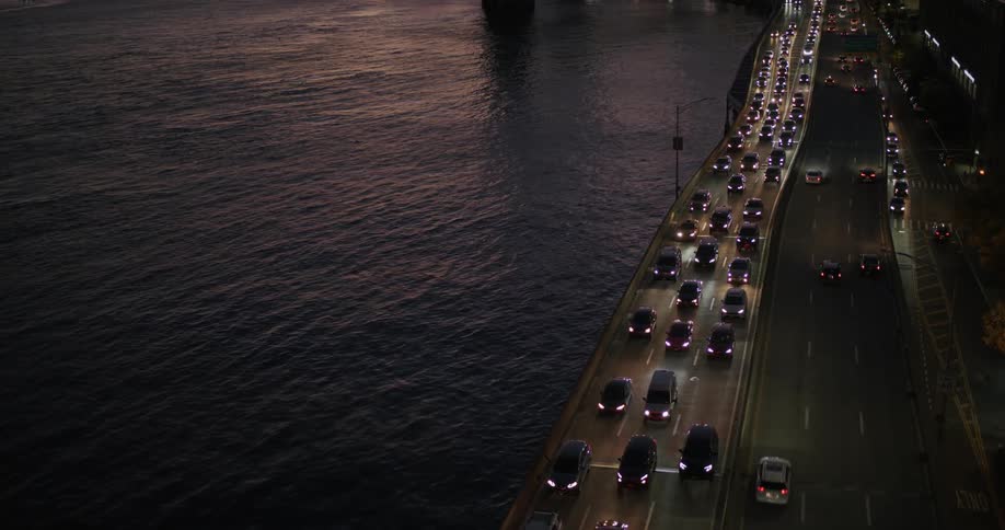 Heavy traffic crossing a bridge as light reflects on the water