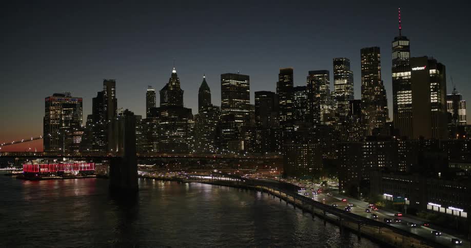 An aerial view of the new york city skyline at night with the brooklyn bridge in the foreground