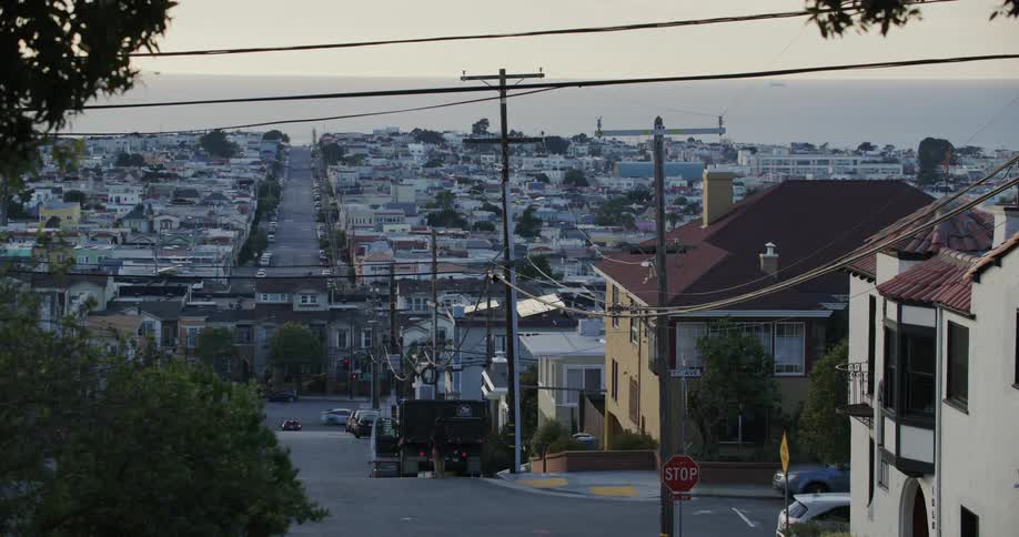 Men work with commercial truck parked on road overlooking busy residential street