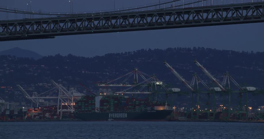 A cargo ship docked and several cranes alongside