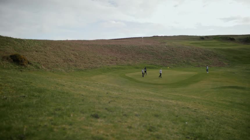 Three people playing golf on a cloudy day