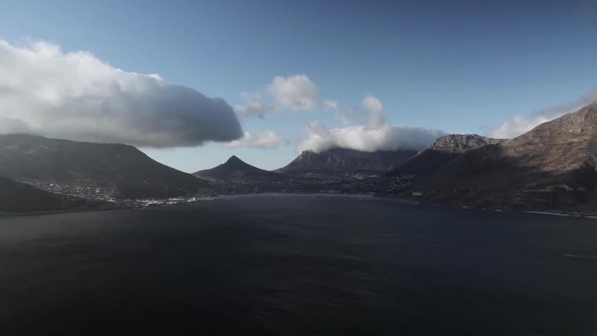 Clouds hover over mountains and ocean