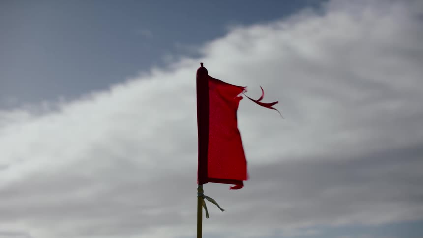 The red tattered flag blows in the wind