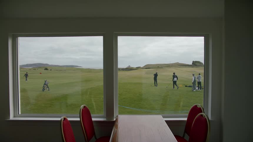 People playing golf seen through the main hall window