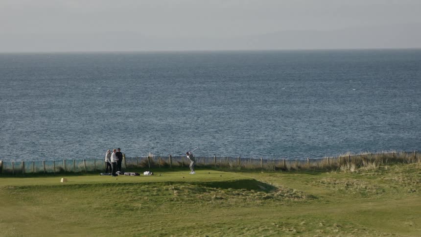 People playing golf on a seaside course