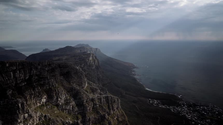Sunlight shines through clouds onto a rocky cliffside