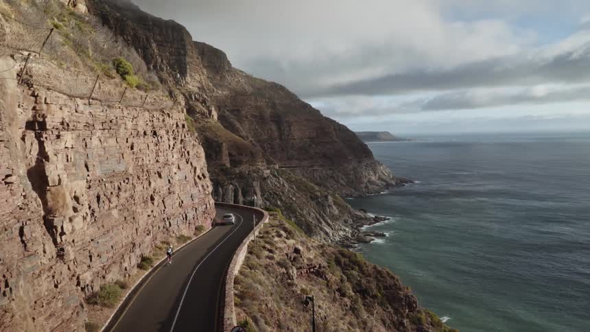A car and bicycle ride on a road by the side of a cliff