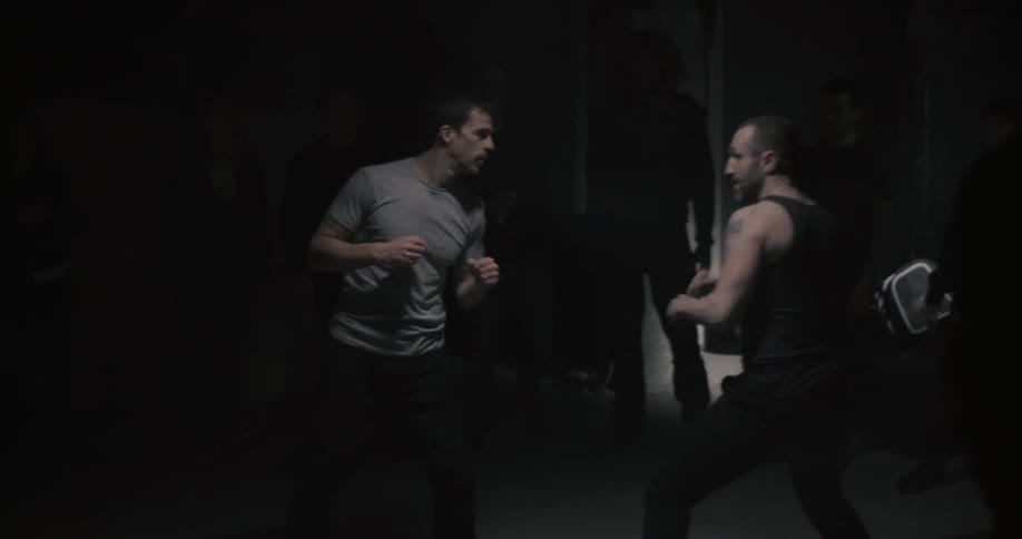 Two men are bare first fighting in a dark hall