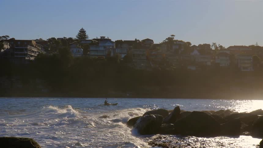 A person is rowing in a canoe in rough waters