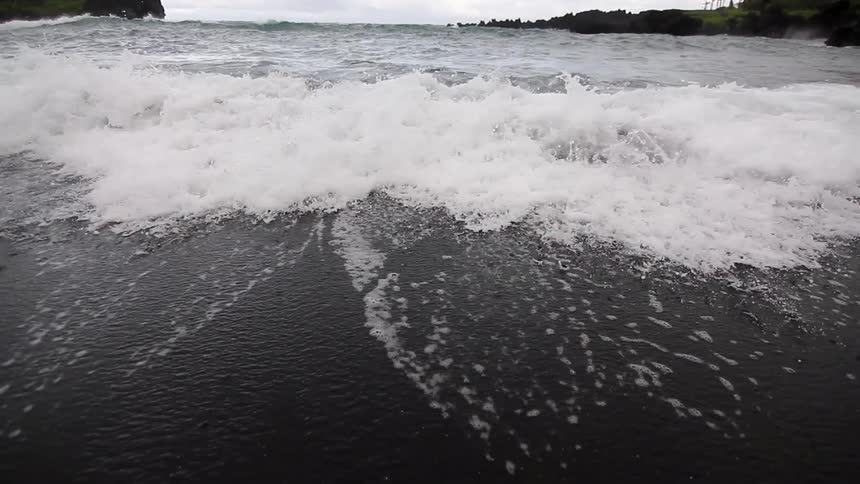 Waves crash on the beach on a cloudy day