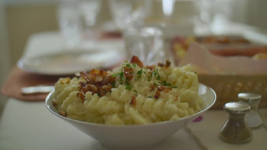Bacon is dropped onto a bowl of mashed potatoes
