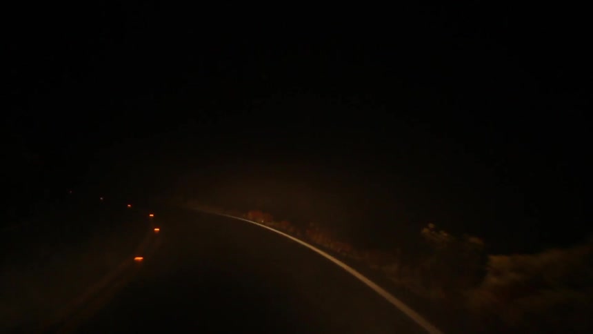 A car drives down a dark road