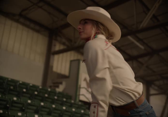 A woman climbs over the railing in the rodeo arena
