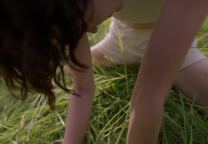 Young thin woman dances stretching on a field of green grass