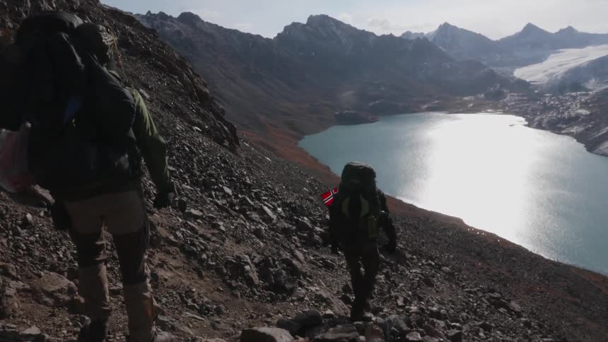 People on a hike in a rocky mountain with a small body of water during the day
