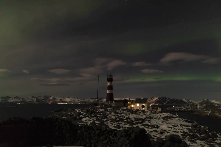 Panorama of the northern lights over snowcovered mountains and an observation tower
