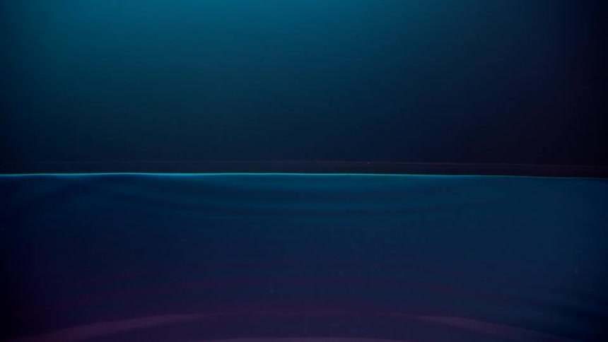 A drop and splash on a neon lightened water surface