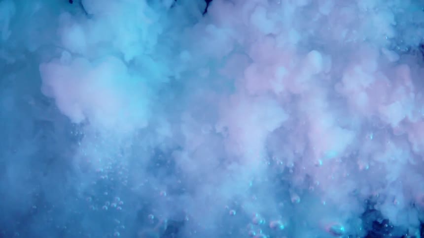 White liquid injected into neon colored water creating clouds