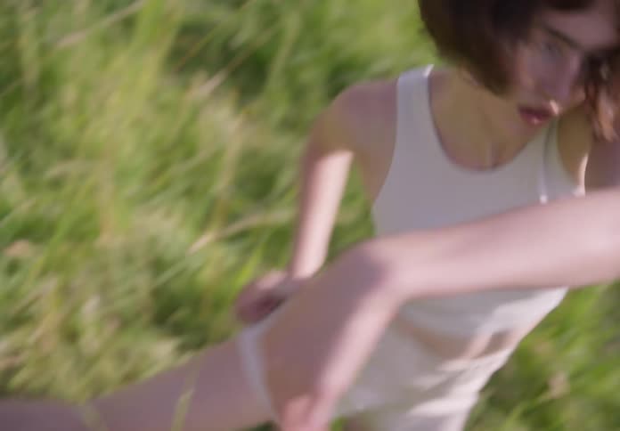 Woman with bob haircut dances outdoors in grassy field