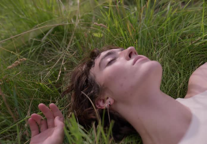 A woman is lying on the grass and smiles quickly