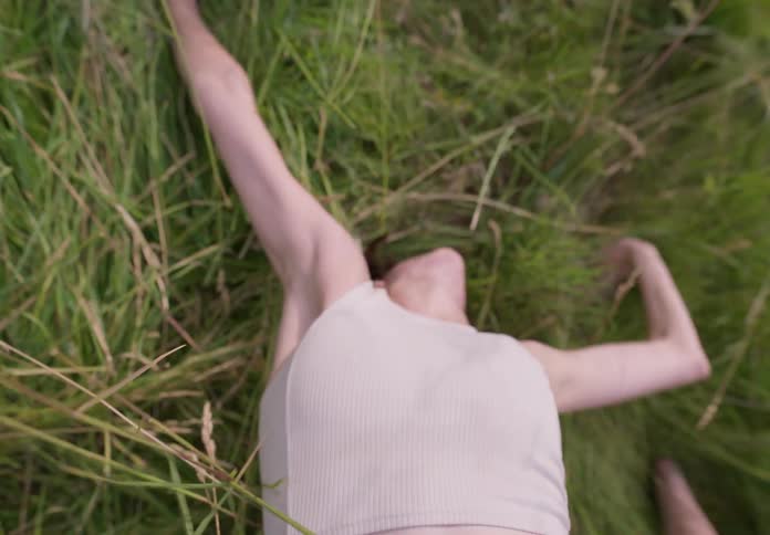 A white woman lying on the grass as she dances
