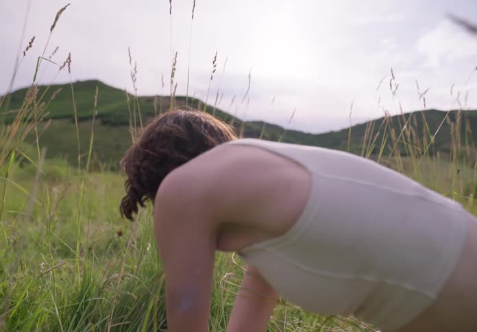 A woman leans down to touch the grass