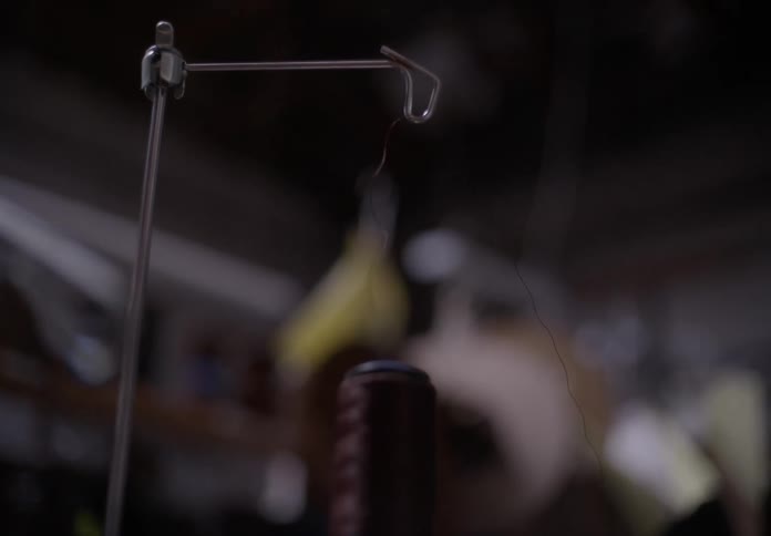 Closeup of a brown thread spool passing through a rod