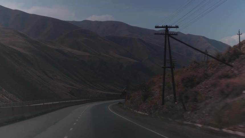 View from a vehicle on a deserted road between mountains