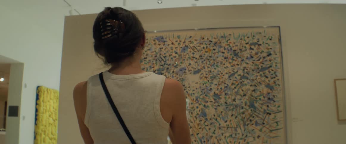 Womans back as she picks up her phone and takes a photo of a piece of art