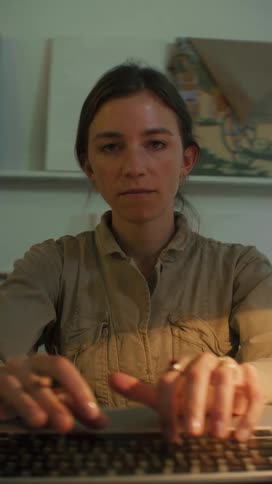 A woman typing on a computer and making notes in a notebook