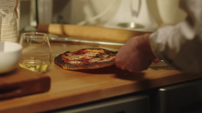 Man cuts a pizza using a pair of scissors
