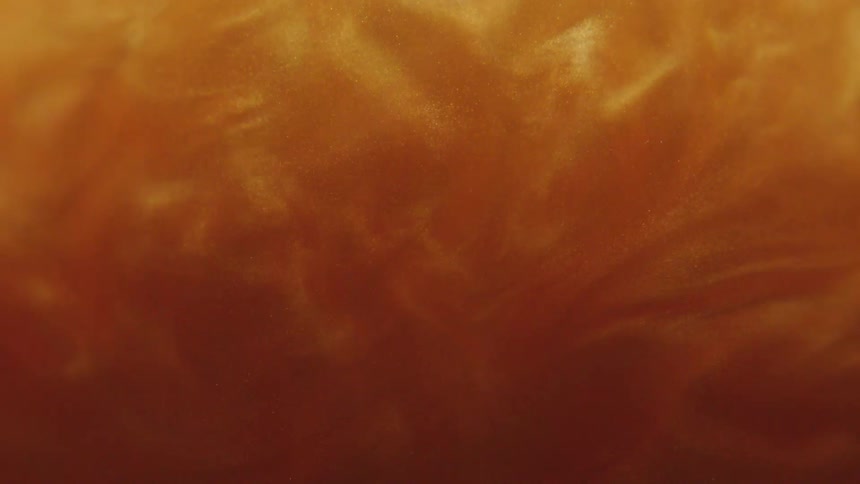 Dense and abstract fluid with a shiny golden hue in slow motion
