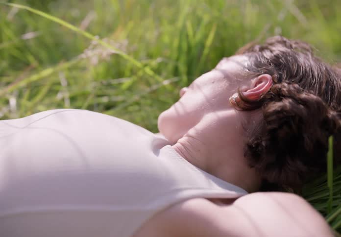 A woman lying on the grass rolling and wiggling around