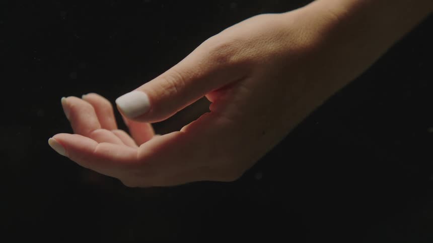 Close up of the hand of a woman against a black background