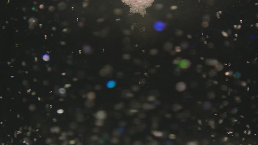 Bright glitter within water in a spiral motion gradually coming to a stop