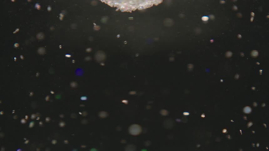 Swirling shiny particles floating in water