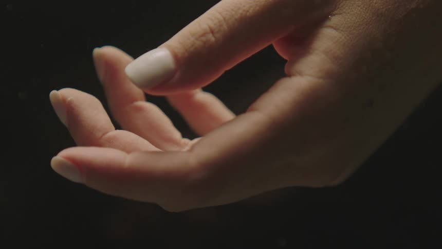 Extreme closeup of a womans hand with whitepainted nails
