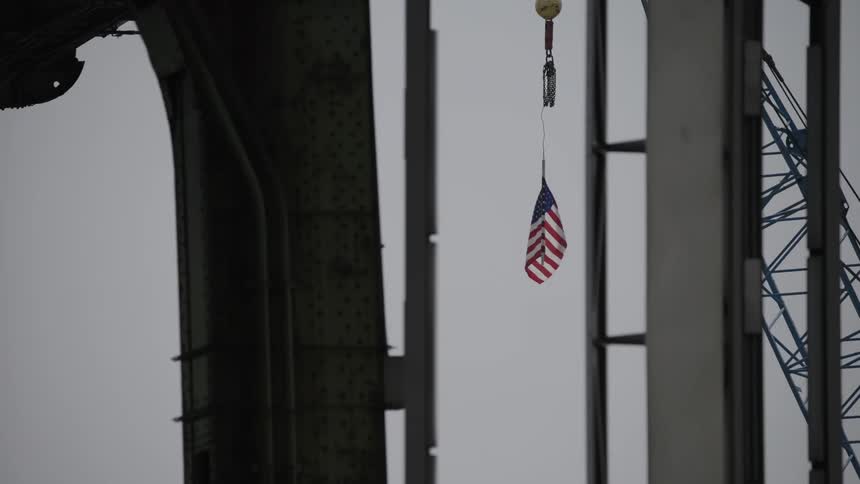 View of the united states flag hanging on a crane on a cloudy day