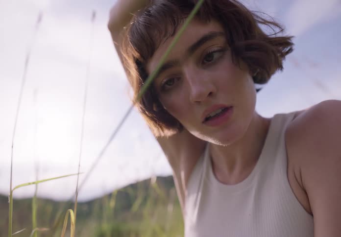 Young thin woman dances stretching on a field of green grass