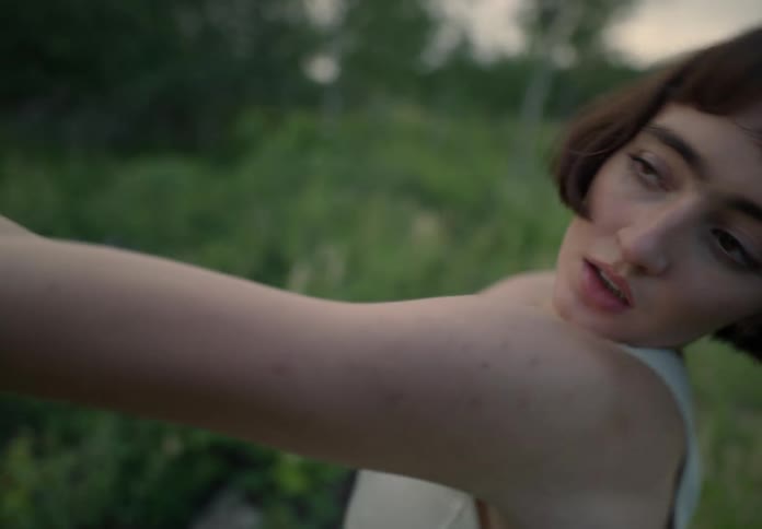 Portrait of a young woman dancing while seated in a natural environment