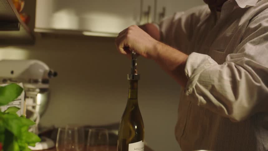 Person opens wine bottle with corkscrew