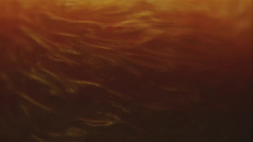 Thick amber shimmering liquid swirling