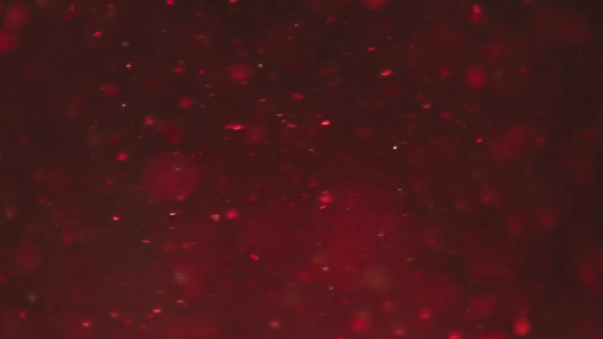 Glitter spinning inside a red liquid