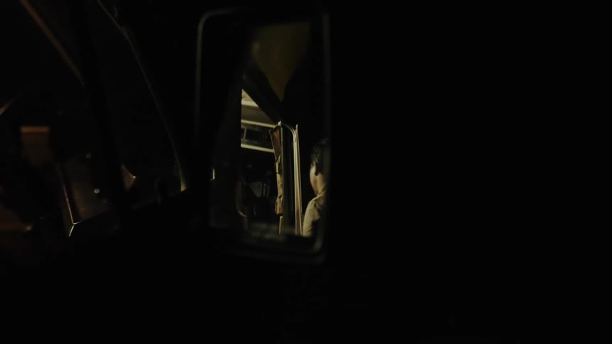 A man is shown in a trucks side view mirror walking away