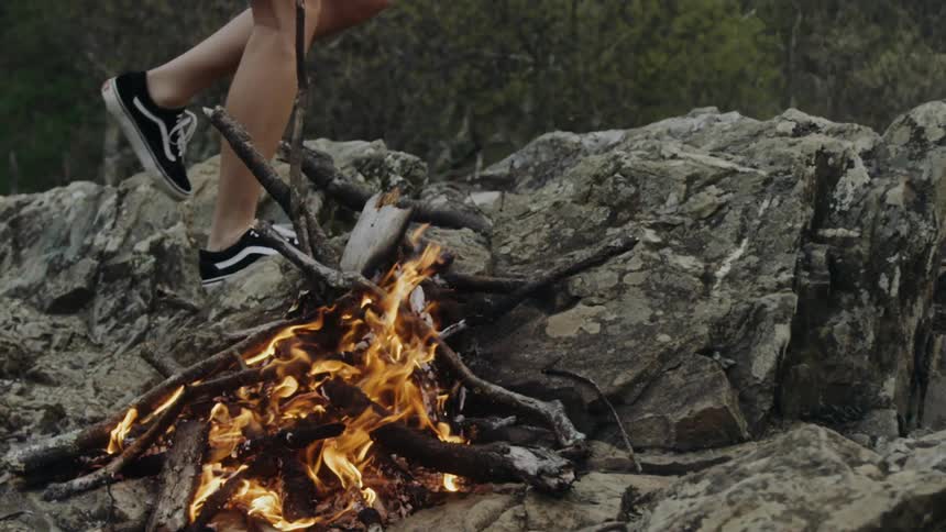 A person walking around a campfire