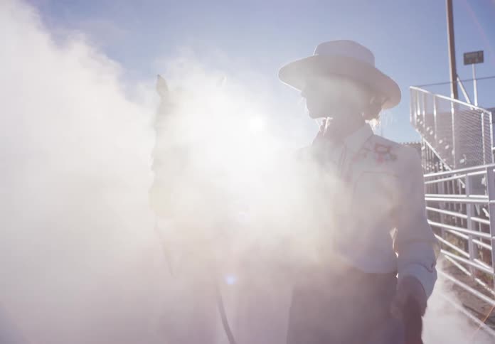 A woman riding a horse in a rodeo arena