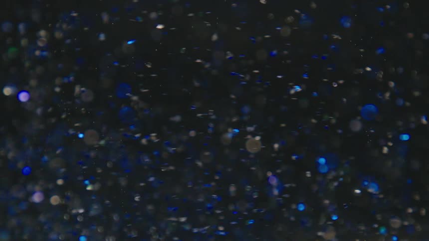 Extreme closeup of glitter in water in slow motion
