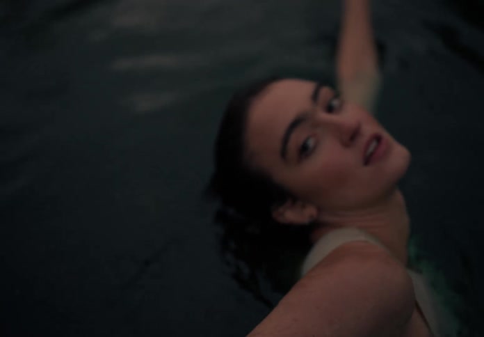 Woman with bob hairstyle and a white tank top dances in water
