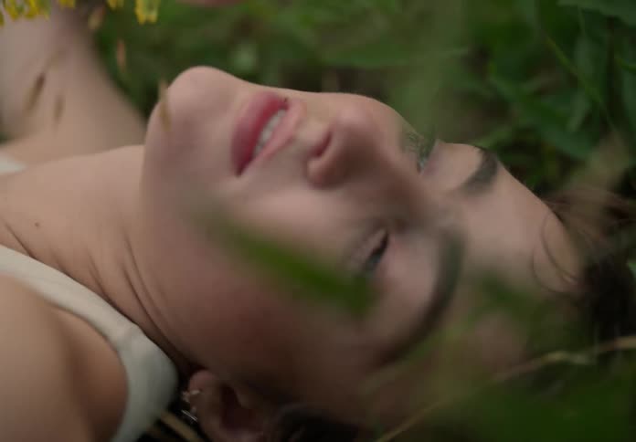 Closeup of a young woman lying on the grass with yellow flowers