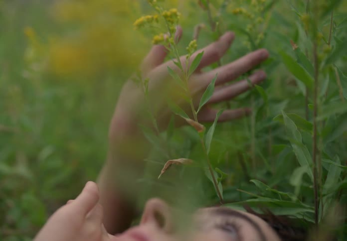 A woman lying on the grass running her hands through the plants